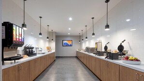 Una cocina moderna con armarios de madera, una cafetera, un fabricante de gofres y un frutero.