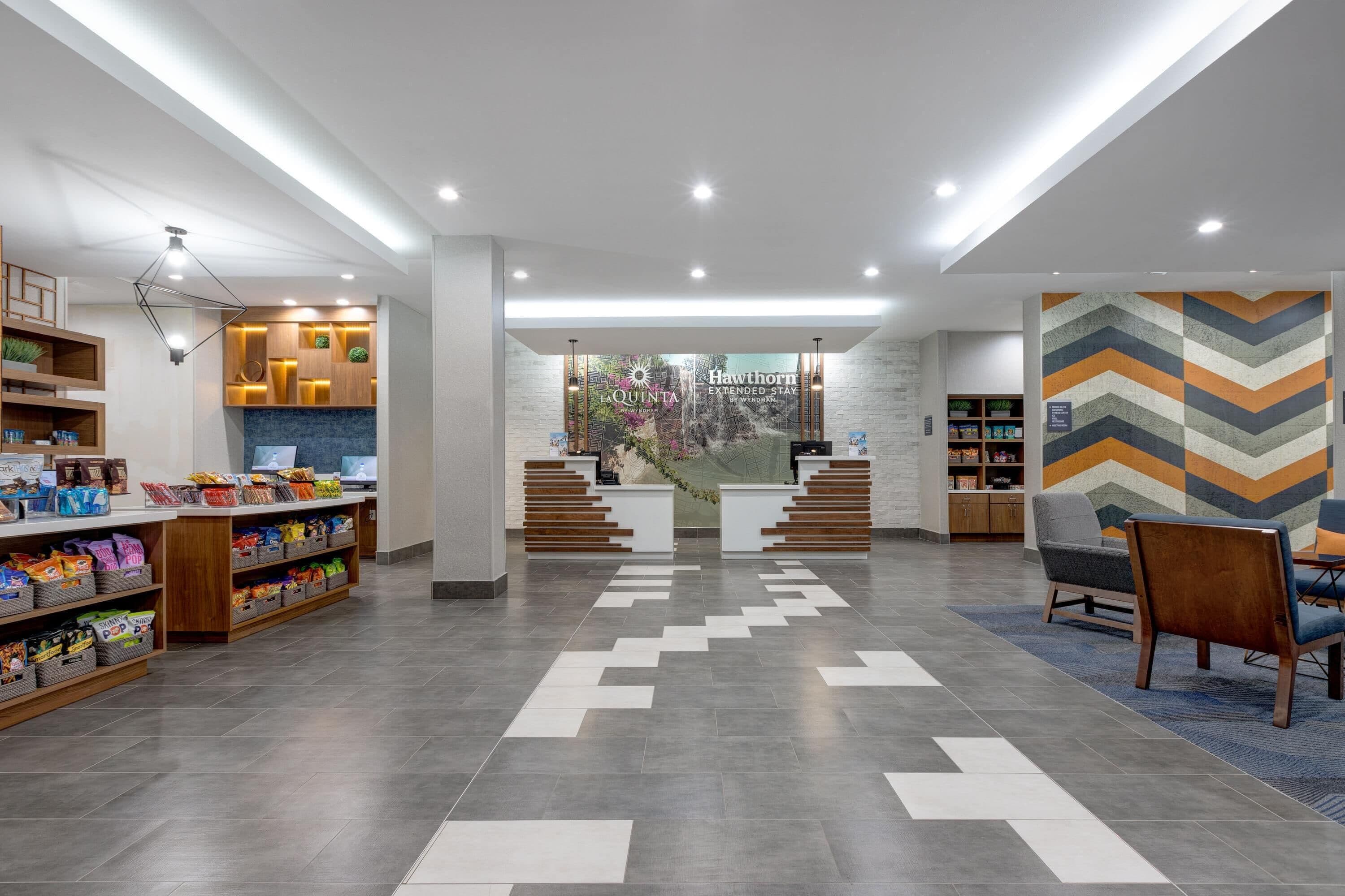 A modern lobby with a reception desk, seating area, and a display of snacks.