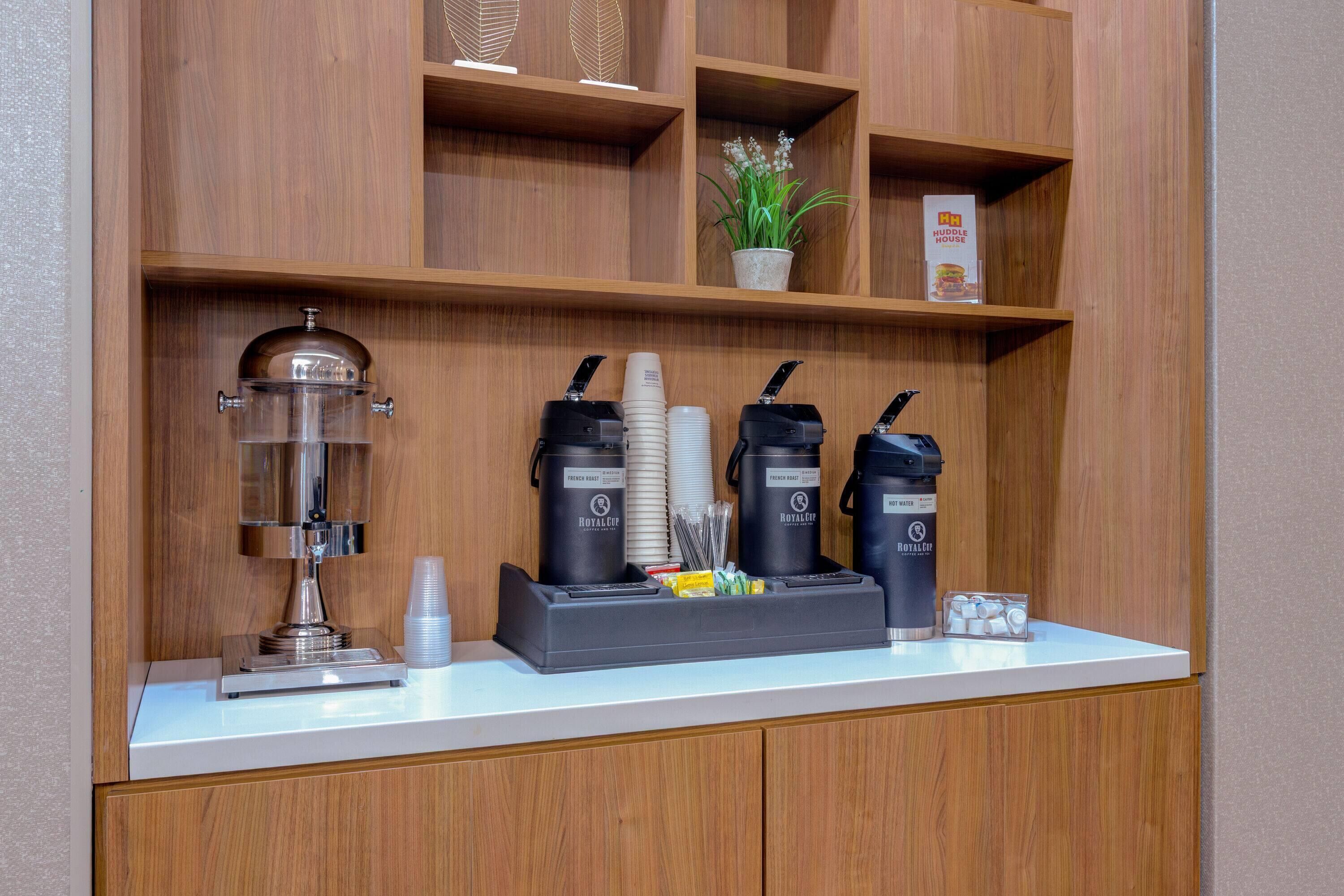 A coffee station with a coffee grinder, two espresso machines, and a coffee dispenser.