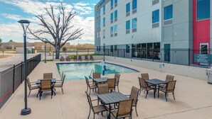 Un hotel con piscina, mobiliario exterior y fachada de edificio moderna.