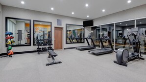 Un gimnasio moderno con cintas de correr, elípticas y pesas libres.