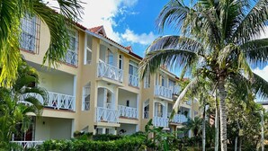 A multi-story hotel with balconies, surrounded by lush greenery and palm trees.