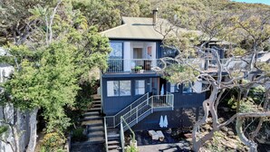 A two-story house with a balcony, surrounded by trees and a rocky landscape. - Great Views, Walk To Beach and Bay In Bush Setting (KILLCARE)