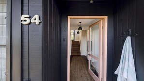 A hallway with a dark wooden door marked with the number 54, leading to a staircase and a room with a hanging towel. - Great Views, Walk To Beach and Bay In Bush Setting (KILLCARE)