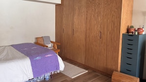A bedroom with a bed, wooden wardrobe, and a small desk with drawers. - World Cup stay - Central location next to Condesa, Escandon neighborhoods. (Ciudad de México)