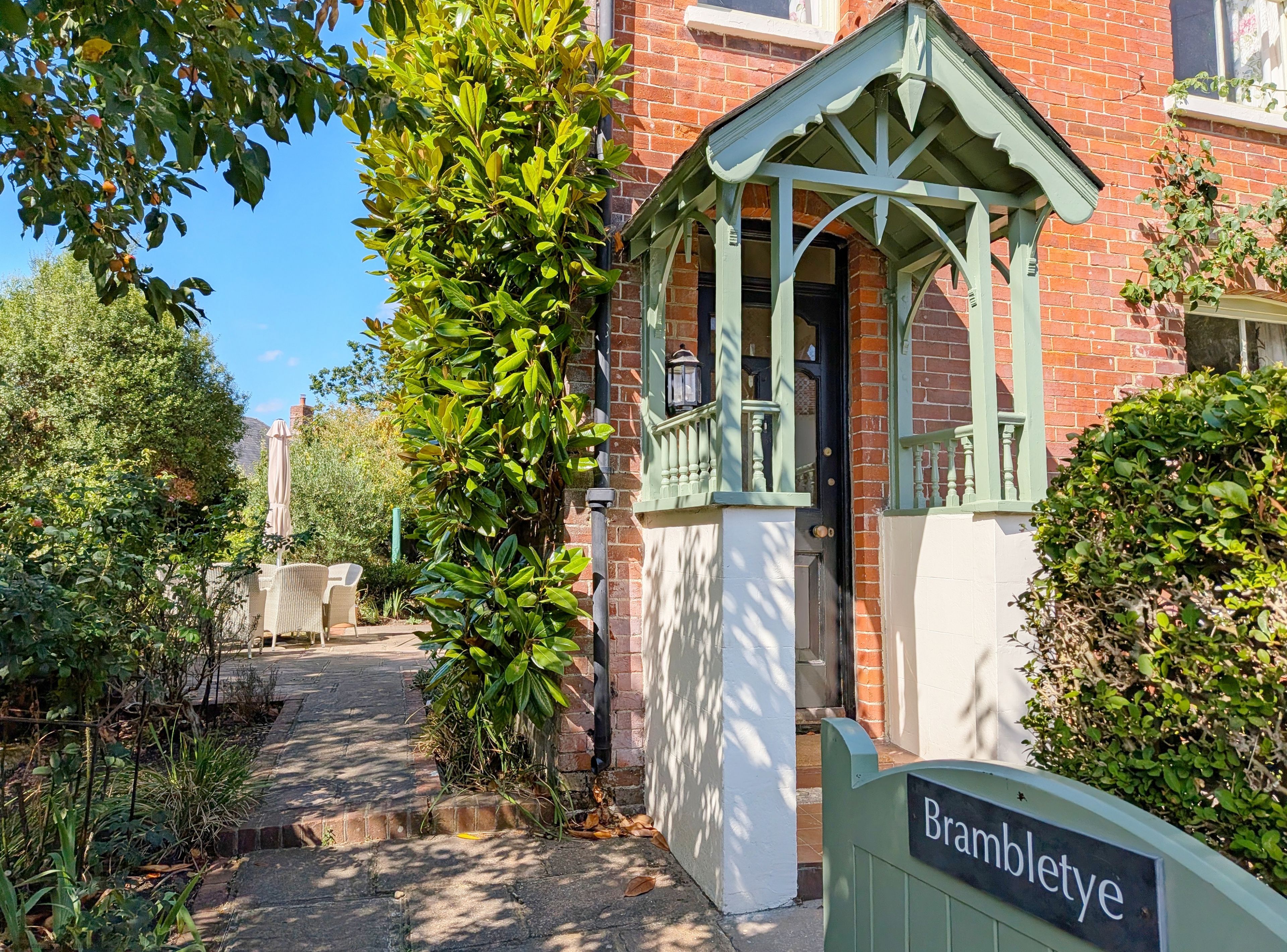 A traditional house with a green porch and a sign reading 'Brambletye.'