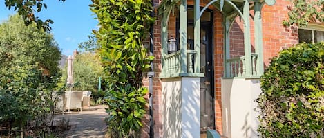 Una casa tradicional con un porche verde y un letrero que dice 'Brambletye'.