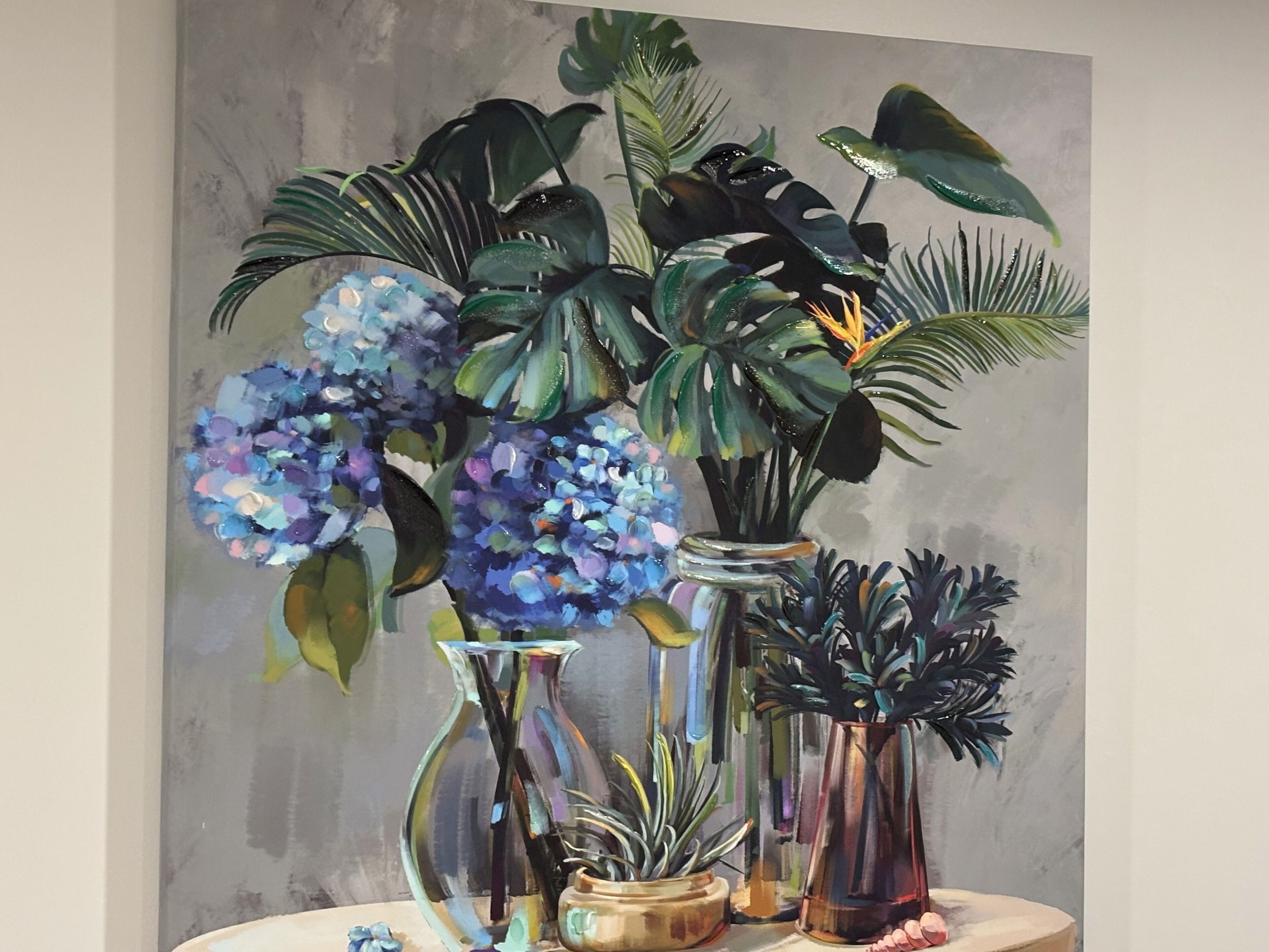 Une nature morte représentant diverses plantes et fleurs dans différents récipients en verre.