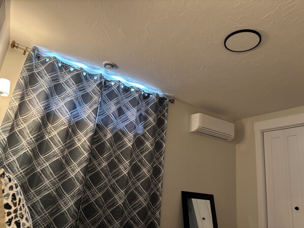 A bathroom with a shower curtain, an air conditioning unit, and a door.