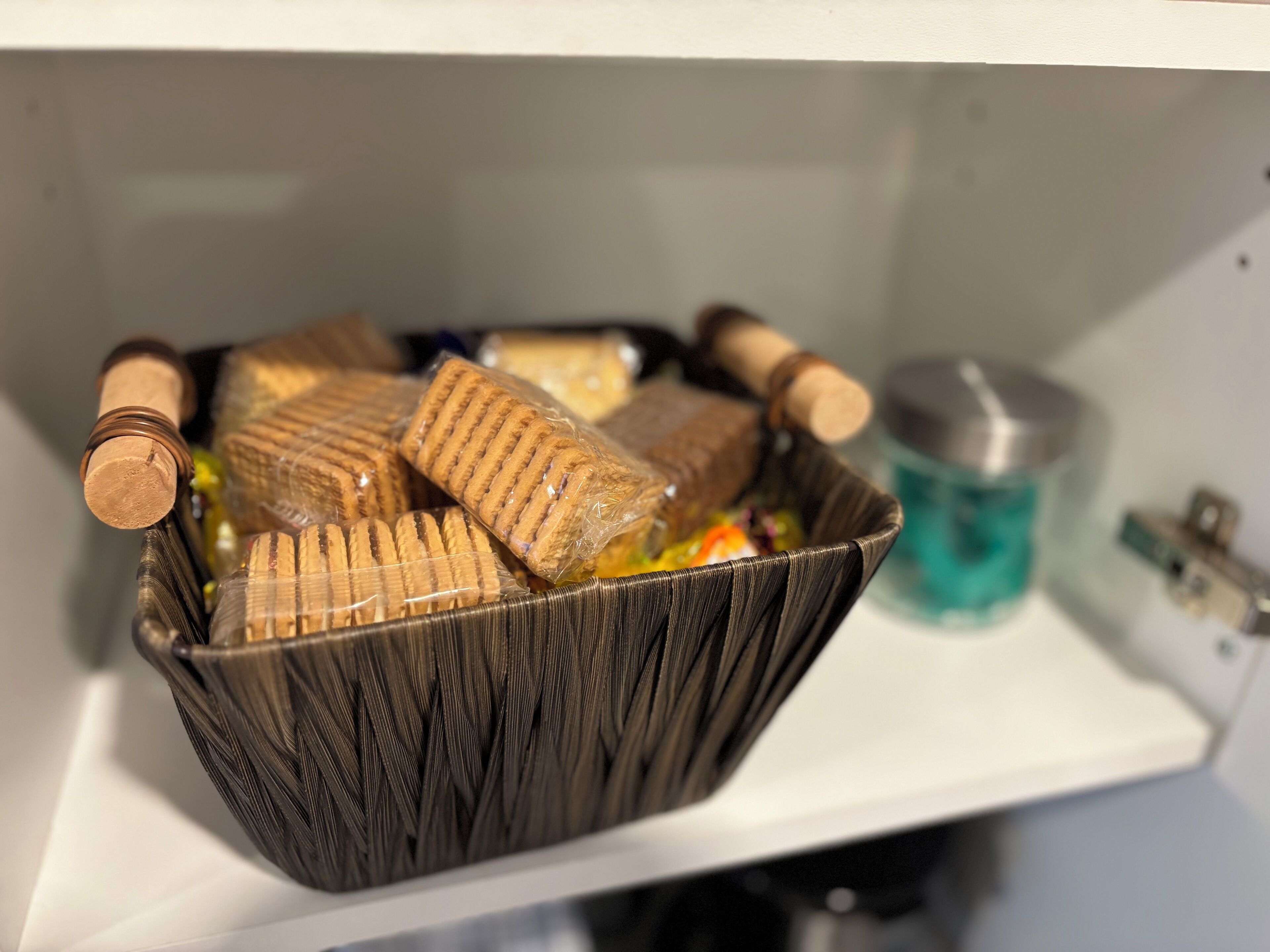 Een rieten mand met verschillende verpakte spullen op een plank.