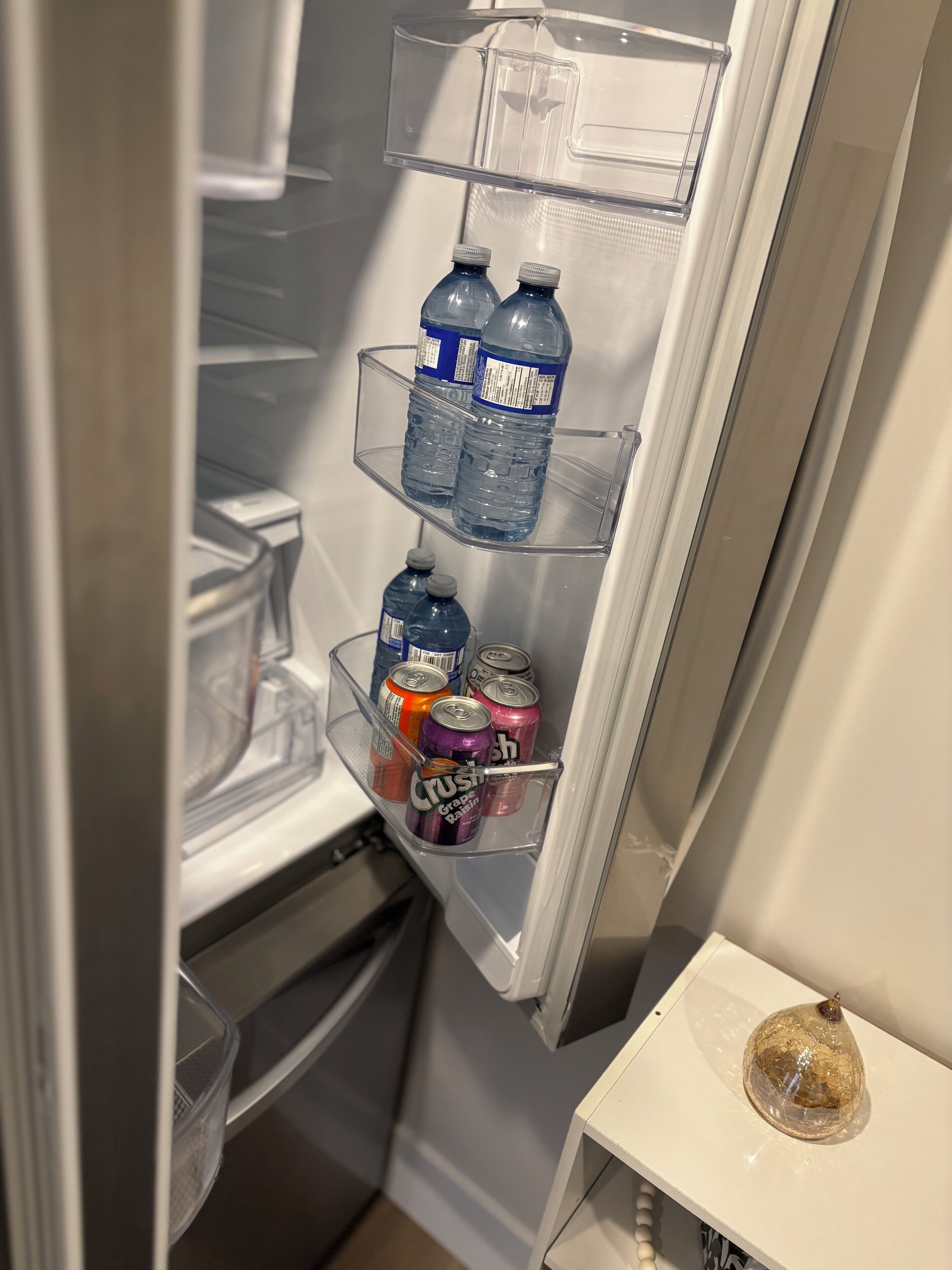 Ein Kühlschrank mit Wasserflaschen und Dosen auf den Türablagen.
