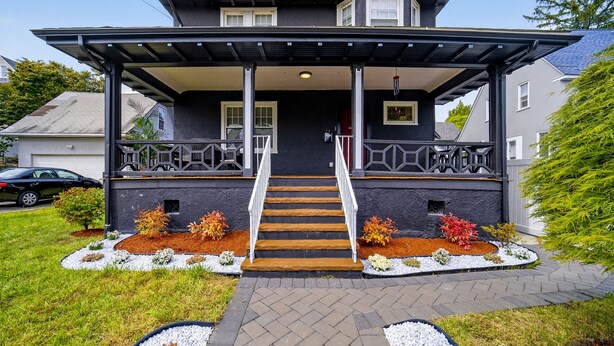 A two-story house with a front porch, a staircase leading to the entrance, and a driveway. - 16 Guest, 10 Bed, Family Getaway- 30 min from NYC (New Rochelle)
