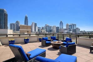 Une terrasse sur le toit, dotée d’un espace extérieur aménagé et d’un foyer, offrant une vue sur le panorama urbain.