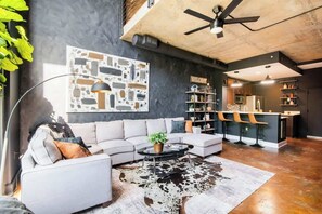 A modern living room with a sectional sofa, a cowhide rug, and a bar area with stools.