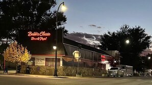 Een gebouw met een neonbord waarop staat 'Bobbie's Classic Diner & Motel' en een geparkeerde vrachtwagen ervoor.