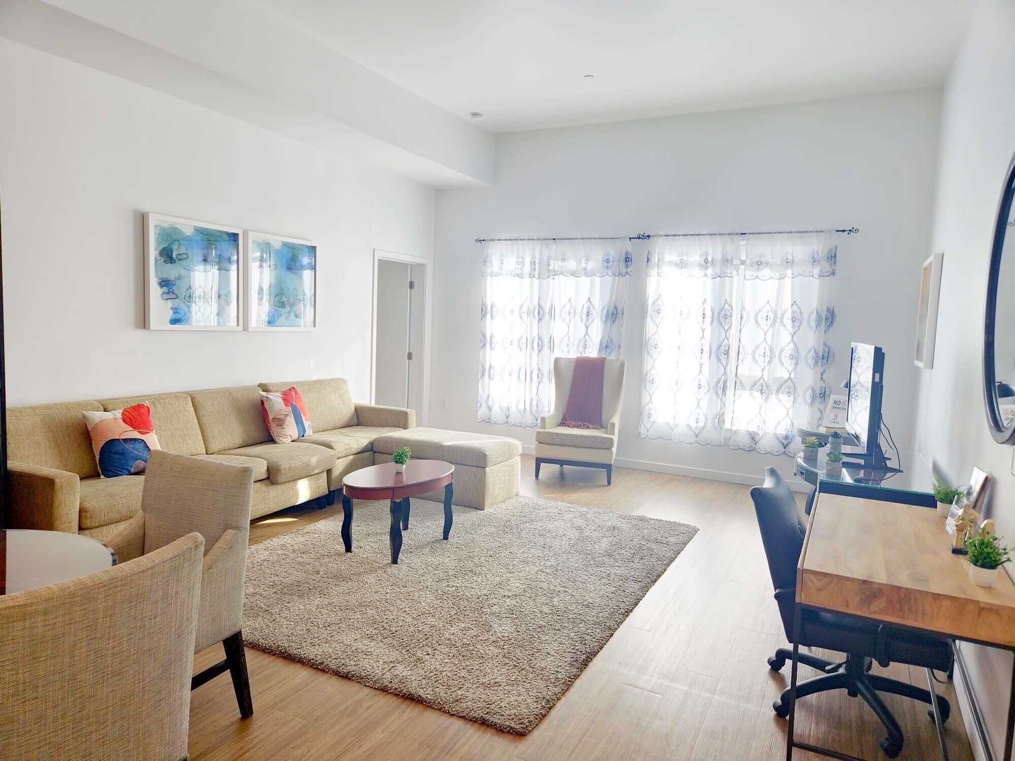A modern living room with a sofa, armchairs, a coffee table, and a desk with a computer.