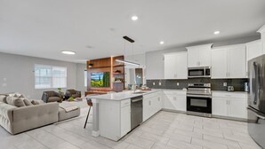 A modern kitchen with white cabinetry, a central island, stainless steel appliances, and a grey tiled floor. -  9BR Luxury Disney Villa Best Location @ Storey Lake Pool, Theater Sleeps 20 (Kissimmee)