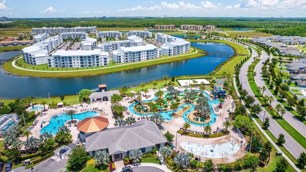 A resort with a central swimming pool, multiple buildings, and a lake. -  9BR Luxury Disney Villa Best Location @ Storey Lake Pool, Theater Sleeps 20 (Kissimmee)