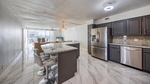 Una cocina moderna con gabinetes oscuros, electrodomésticos de acero inoxidable y una isla grande con taburetes de bar.