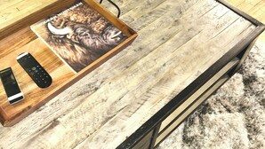 Una mesa de centro de madera con un libro titulado 'Modern Huntsman' y dos controles remotos.