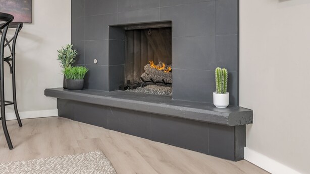 A modern fireplace with a stone surround, a television mounted above it, and two potted plants on either side. - The Desert Rose A Modern home in a great location (Sedona)