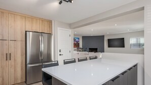A modern kitchen with a large island, stainless steel appliances, and wooden cabinetry. - The Desert Rose A Modern home in a great location (Sedona)