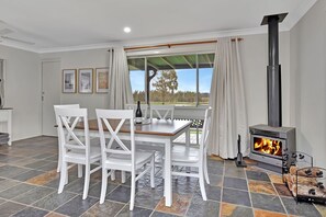 Una habitación con una mesa de comedor, sillas, chimenea y una ventana con cortinas.