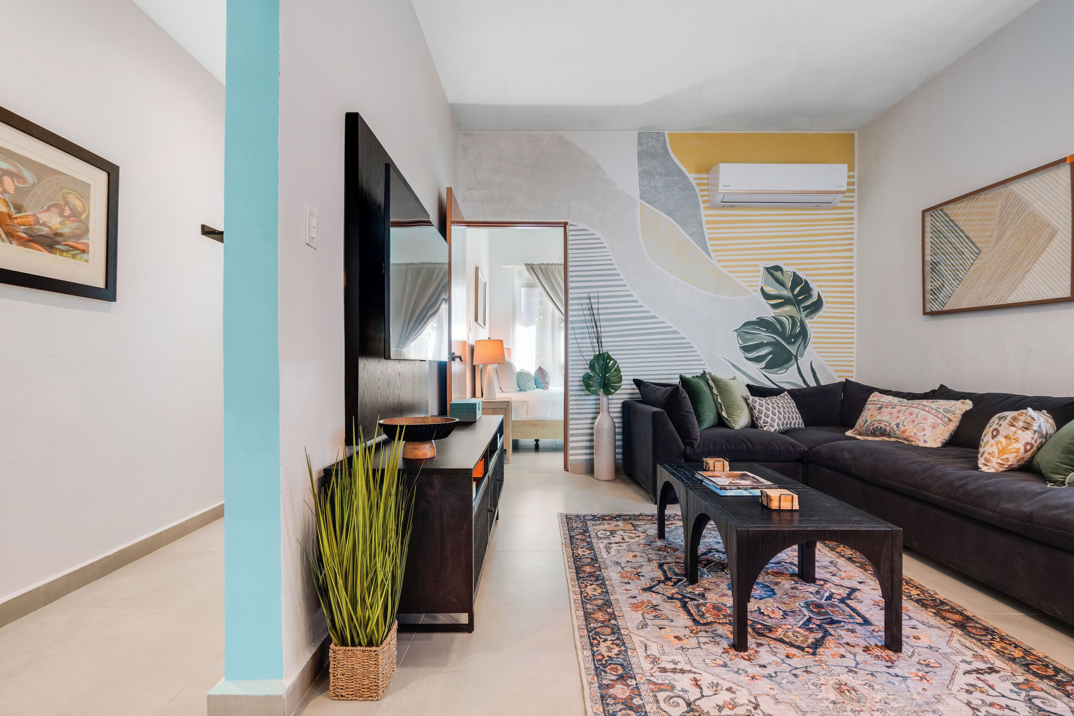 Ein modernes Wohnzimmer mit einem dunklen Sofa, einem Couchtisch, einem großen Spiegel und einer Treppe mit einem einzigartigen Design.