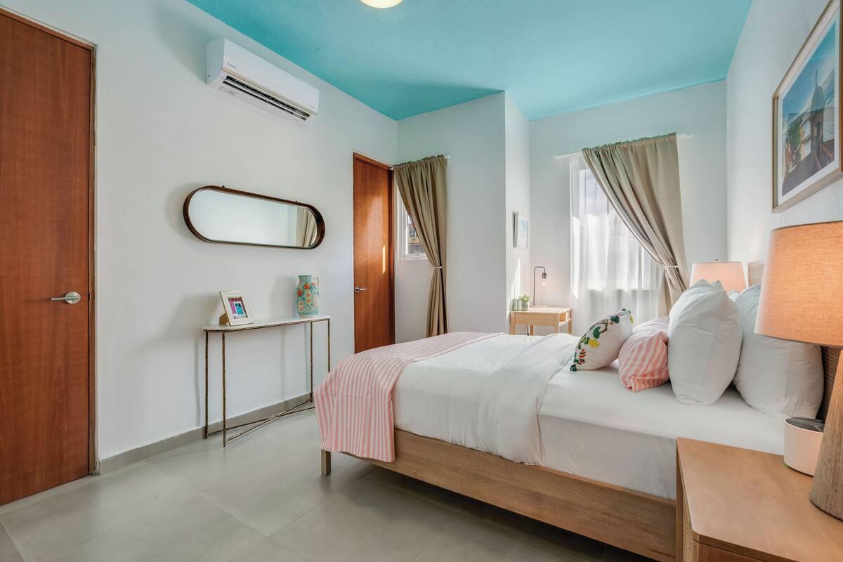 Une chambre à coucher avec un lit, une table de chevet, une lampe et une fenêtre avec des rideaux.