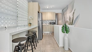 Une cuisine moderne avec un îlot central, des tabourets de bar et une plante décorative.