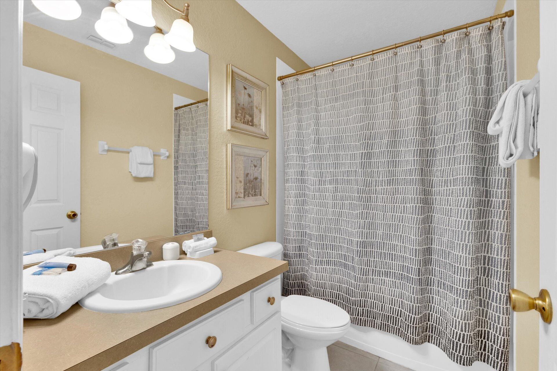 Een badkamer met een wit wastafel, toilet en een douchegordijn met een reliëfprint.