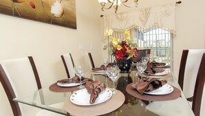 A dining table set for six with placemats, plates, and folded napkins. A vase with flowers is centered on the table. - BCH3043 (Kissimmee)
