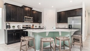 Una cocina moderna con armarios de madera oscura, electrodomésticos de acero inoxidable y una isla central con taburetes.