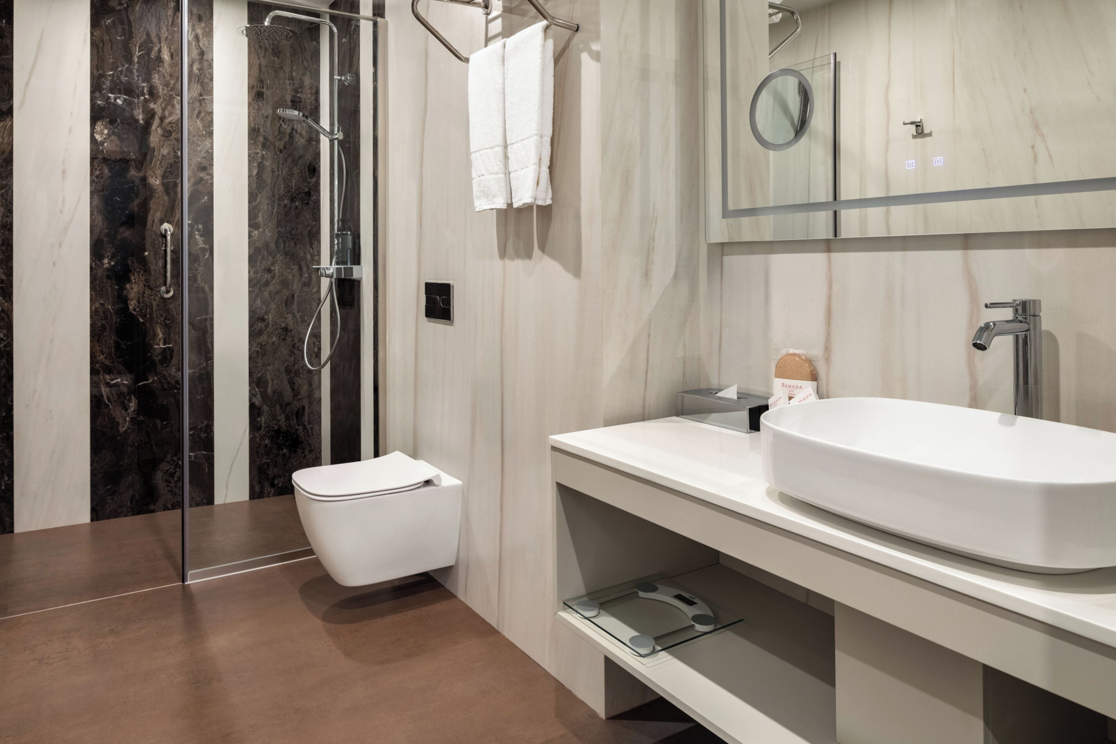 A modern bathroom with a glass-enclosed shower, a white toilet, a large white sink, and a mirror above the sink.