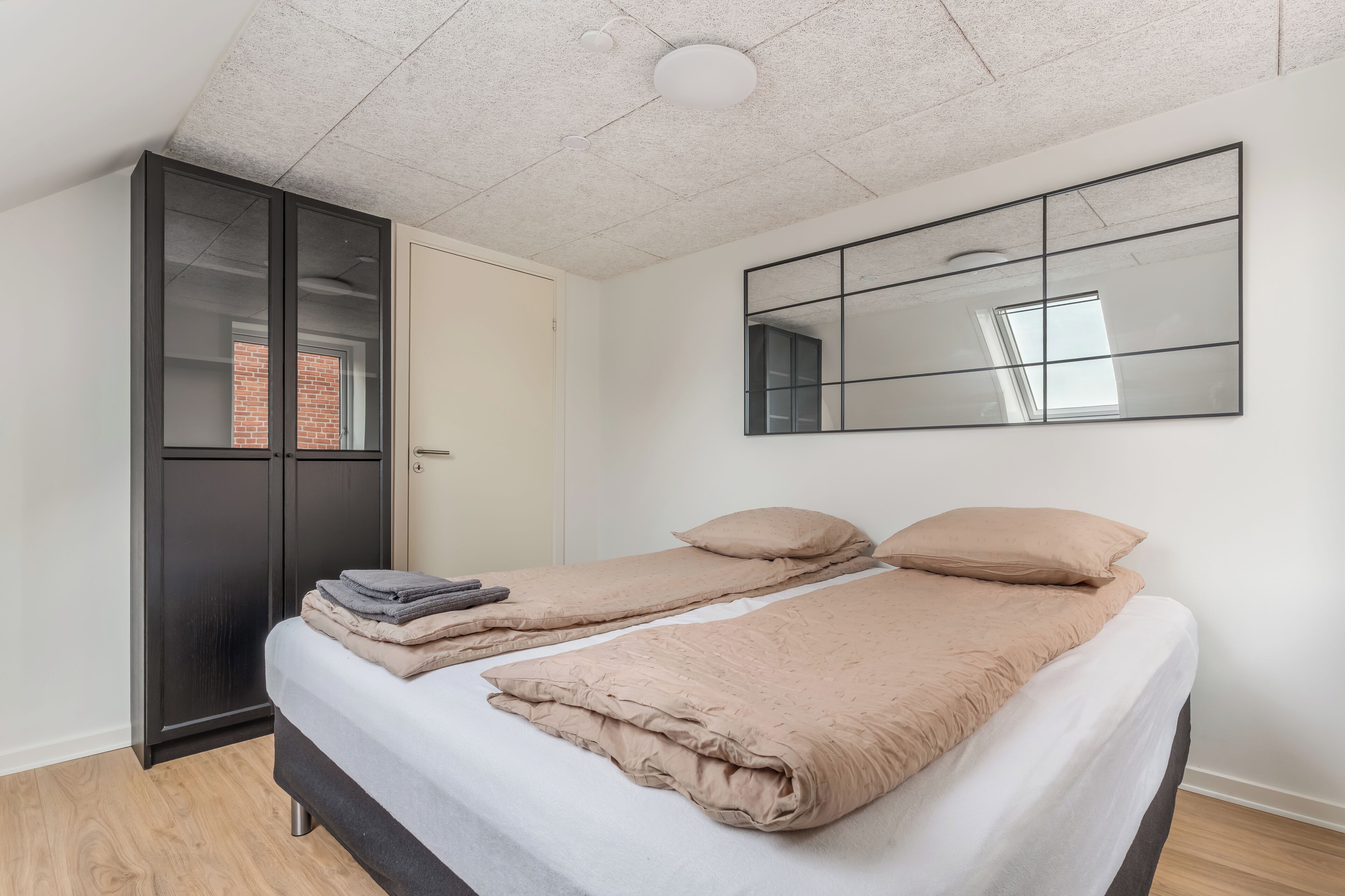 Une chambre à coucher avec un lit, une armoire et un miroir au mur.
