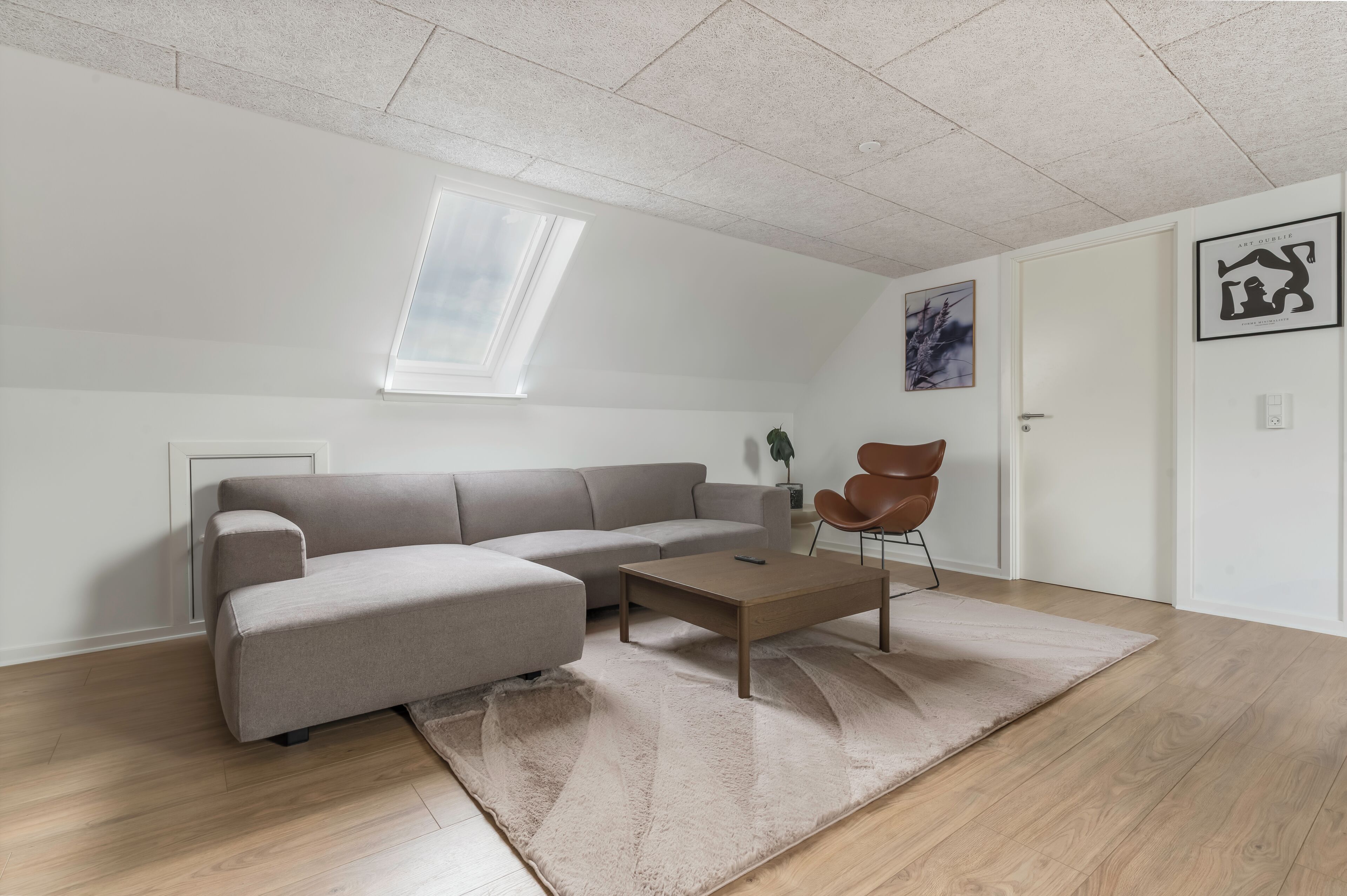 A modern living room with a sectional sofa, a coffee table, and a single chair.
