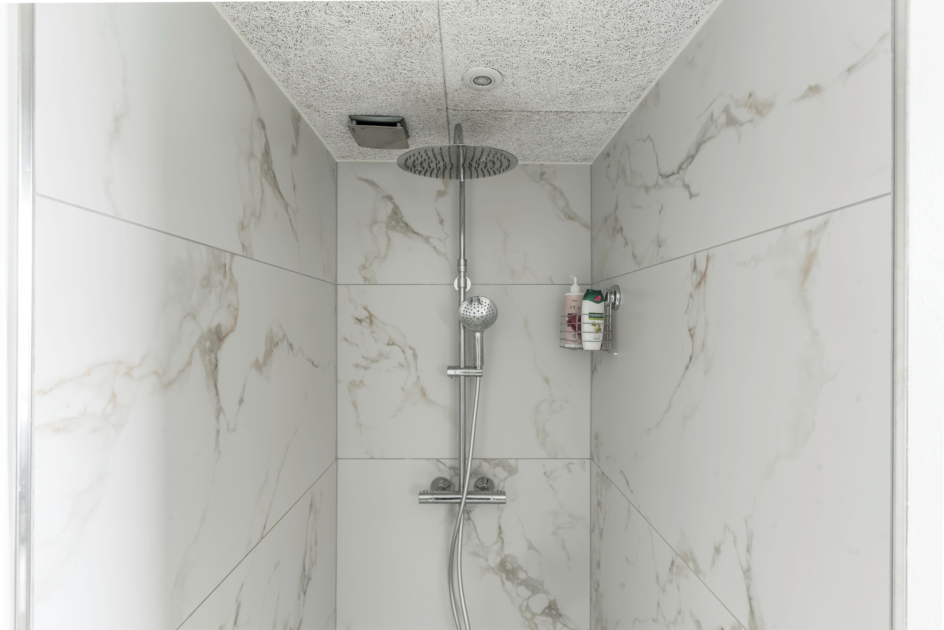 A shower with a rain showerhead, handheld showerhead, and a handheld shower attachment.