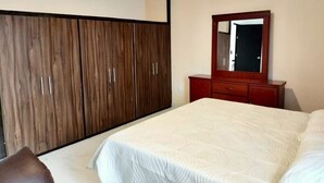 A hotel room with a large bed, wooden wardrobe, and a mirror above a dresser. - Spacious and private apartment (Oaxaca de Juárez)