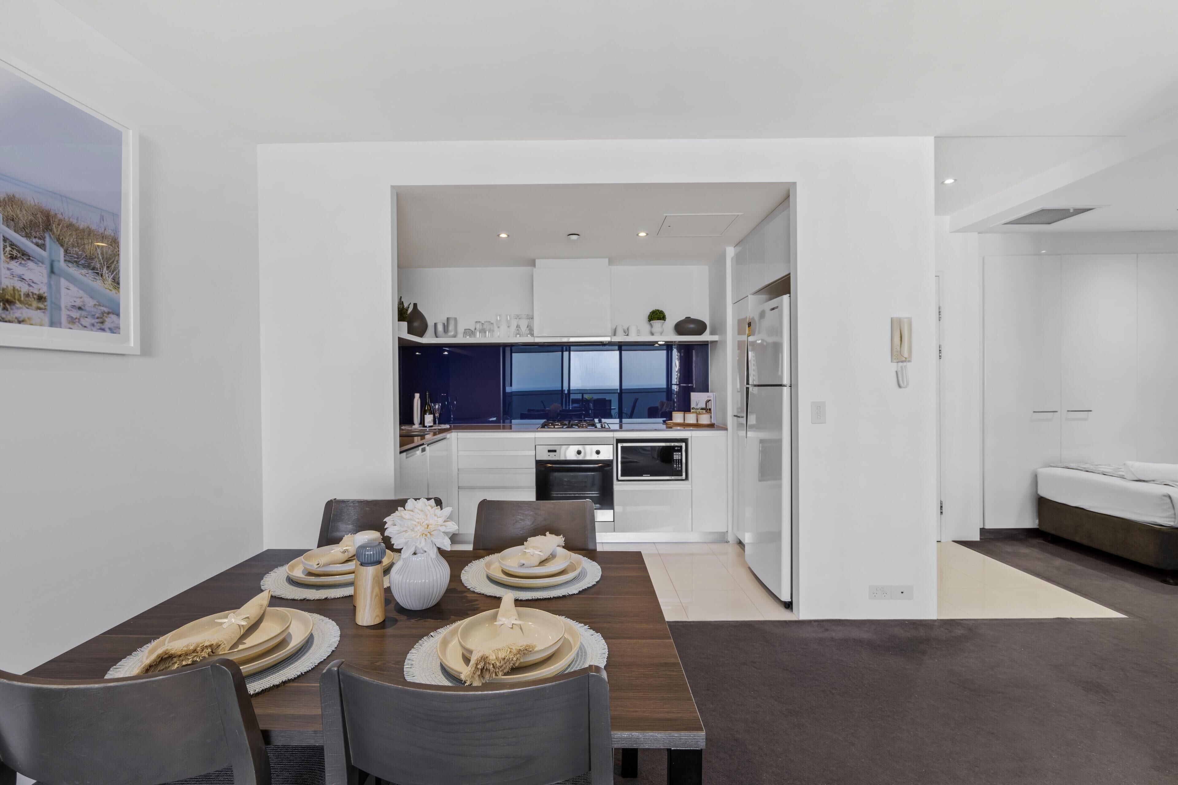 A modern kitchen with white cabinets, a built-in oven, and a large window.
