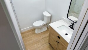 A small bathroom with a toilet, sink, and wooden cabinet. - Stunning Waterfront Condo, Fully Remodeled – Bring Your Boat, No Fixed Bridges! (Boca Raton)