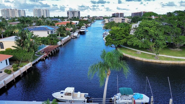 A river with boats docked on the banks, surrounded by residential buildings and greenery. - Stunning Waterfront Condo, Fully Remodeled – Bring Your Boat, No Fixed Bridges! (Boca Raton)