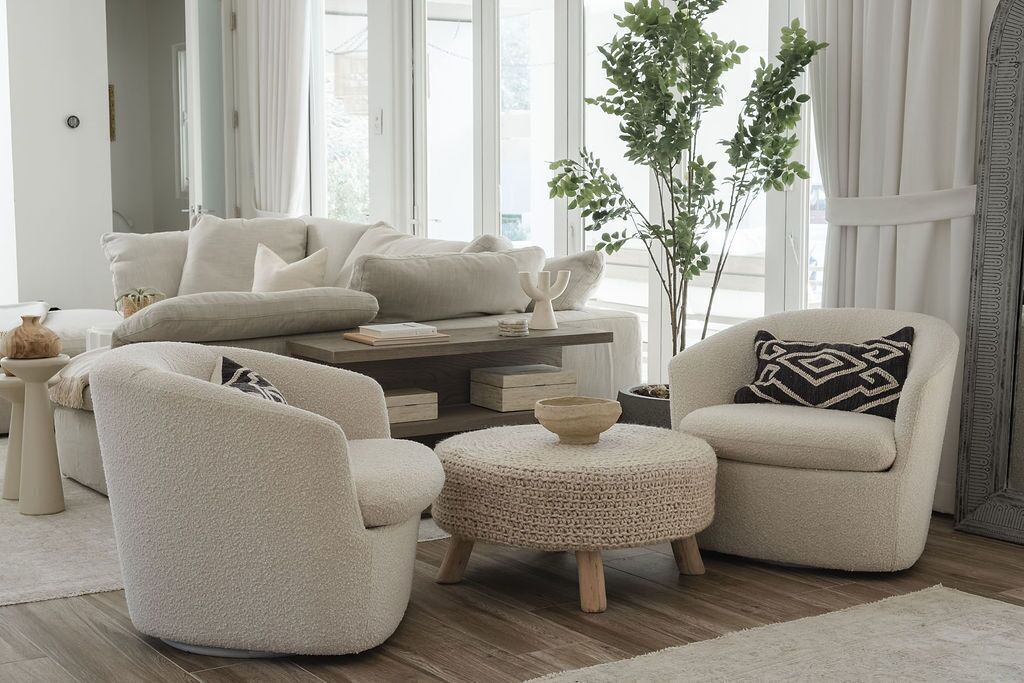 Una sala de estar moderna con un sofá, dos sillones, una mesa de centro y una planta en maceta.
