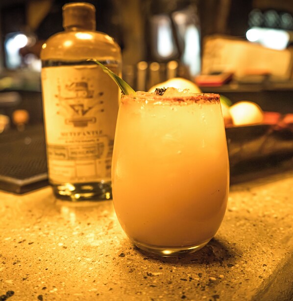A cocktail glass with a straw on a bar counter.