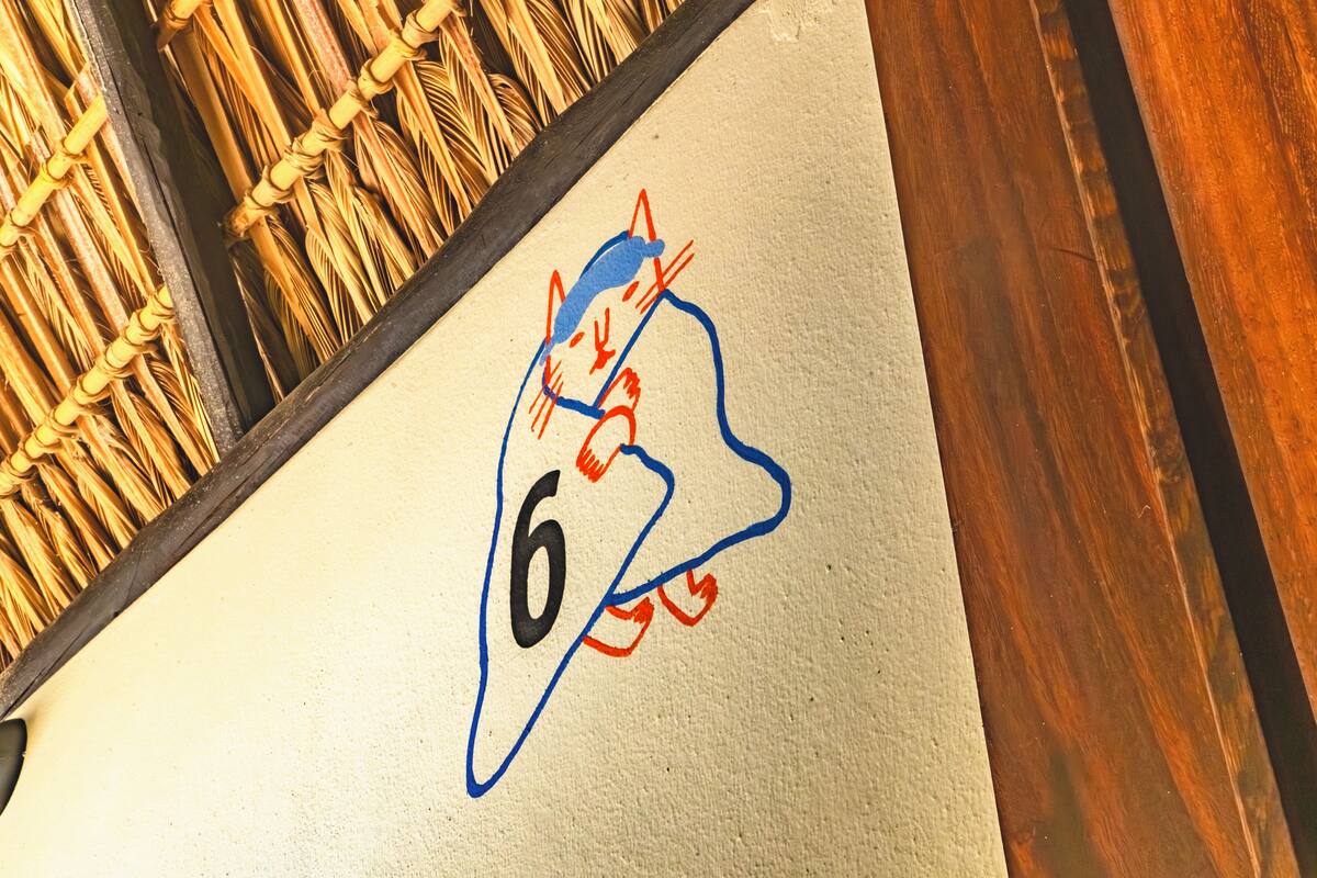 Una pared con el número '6' y un dibujo de un gato en azul y rojo.
