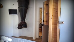 A bedroom with a bed, a large exhaust fan, a wooden door, and a small table with a chair. - Grand loft du Moulin - 2-traveler room near Ancenis (Vair-sur-Loire)