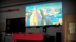 A television mounted on a wall displaying a cityscape. - Grand loft du Moulin - 2-traveler room near Ancenis (Vair-sur-Loire)