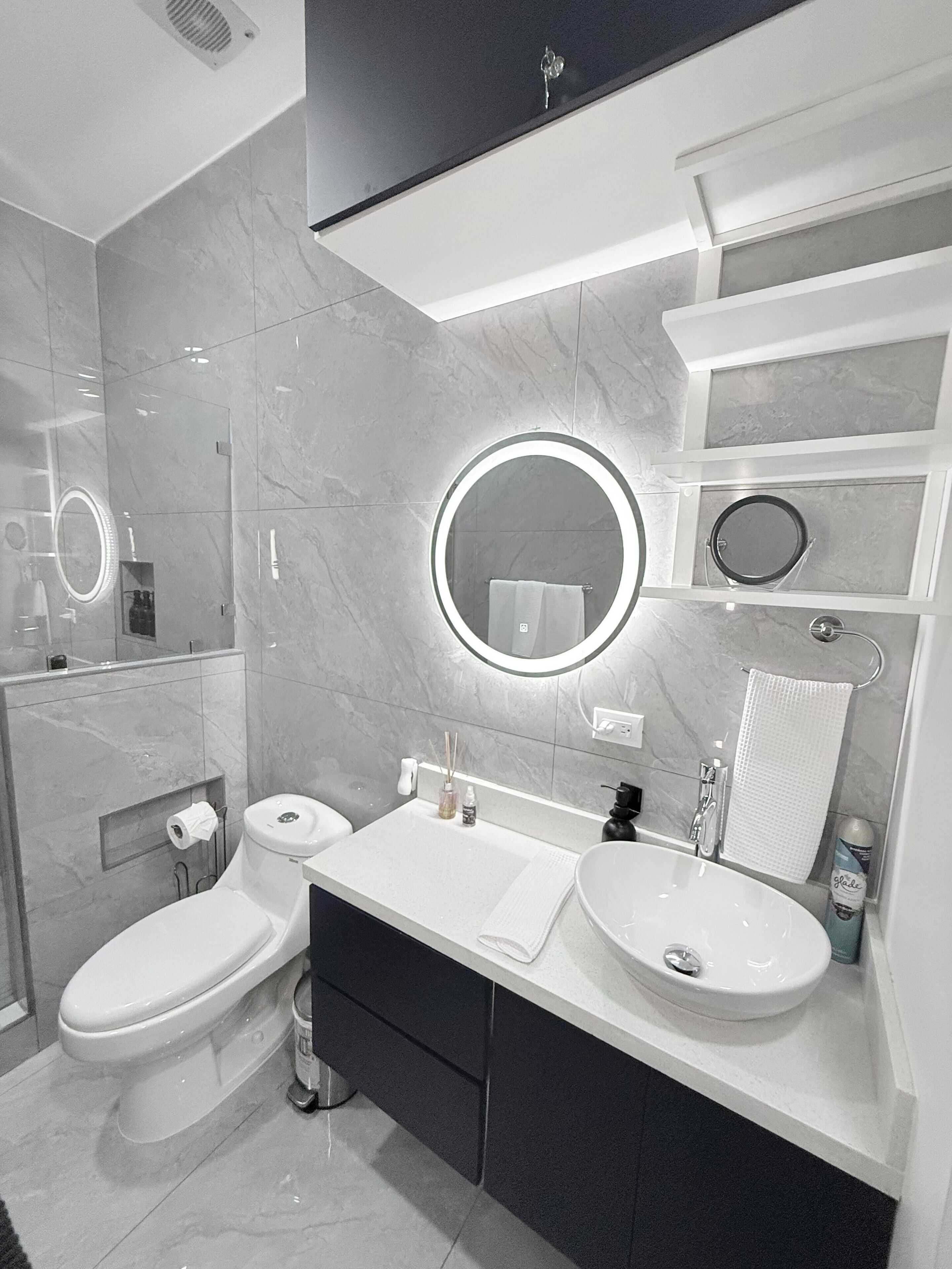 A modern bathroom with two toilets, a vanity with a mirror, and a sink.