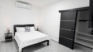 A modern bedroom with a bed, bedside tables, a wardrobe, and an air conditioning unit. - Casa Azul Jaco (Jaco)