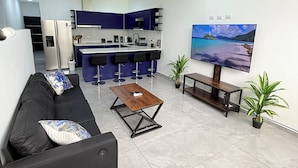 A modern living room with a black sofa, a wooden coffee table, and a large flat-screen TV. - Casa Azul Jaco (Jaco)