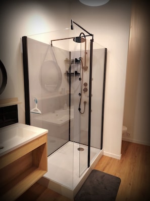 Une salle de bain moderne avec une douche à parois de verre, un meuble-lavabo en bois et un lavabo blanc.